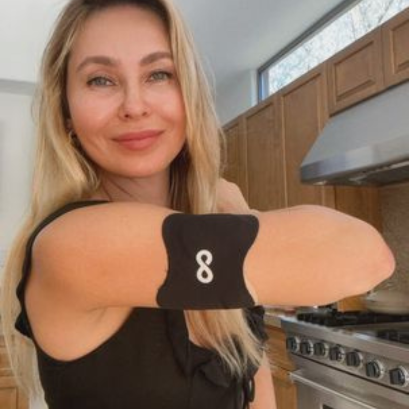 Woman in a kitchen wearing a black arm patch with a white number eight.