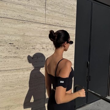 Woman training outdoors, seen from behind, wearing an Ion Layer patch on her upper arm.