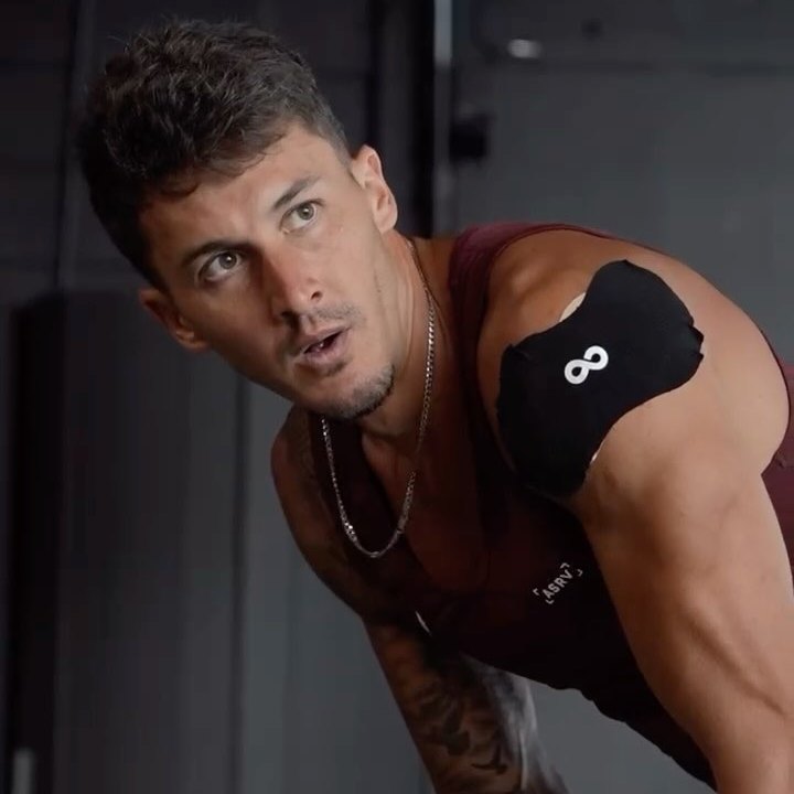 Athlete in a gym wearing an Ion Layer NAD+ patch on his shoulder